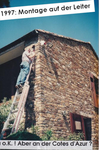Ein Techniker auf einer Leiter montiert eine Außensirene an der Natursteinfassade eines Landhauses an der Cotes d'Azur, 1997.